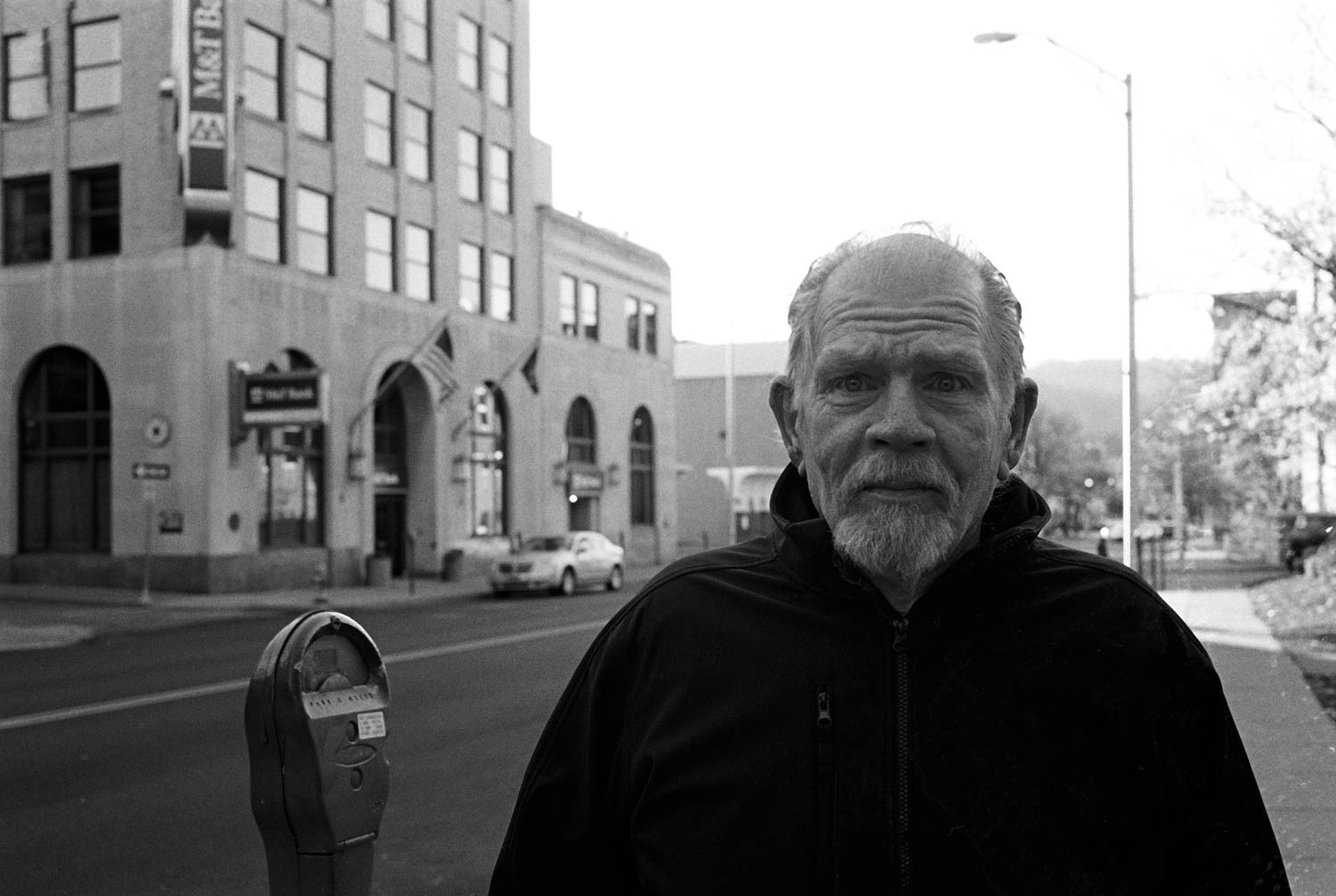 A black and white street portrait of a man standing on the sidewalk in Binghamton, NY