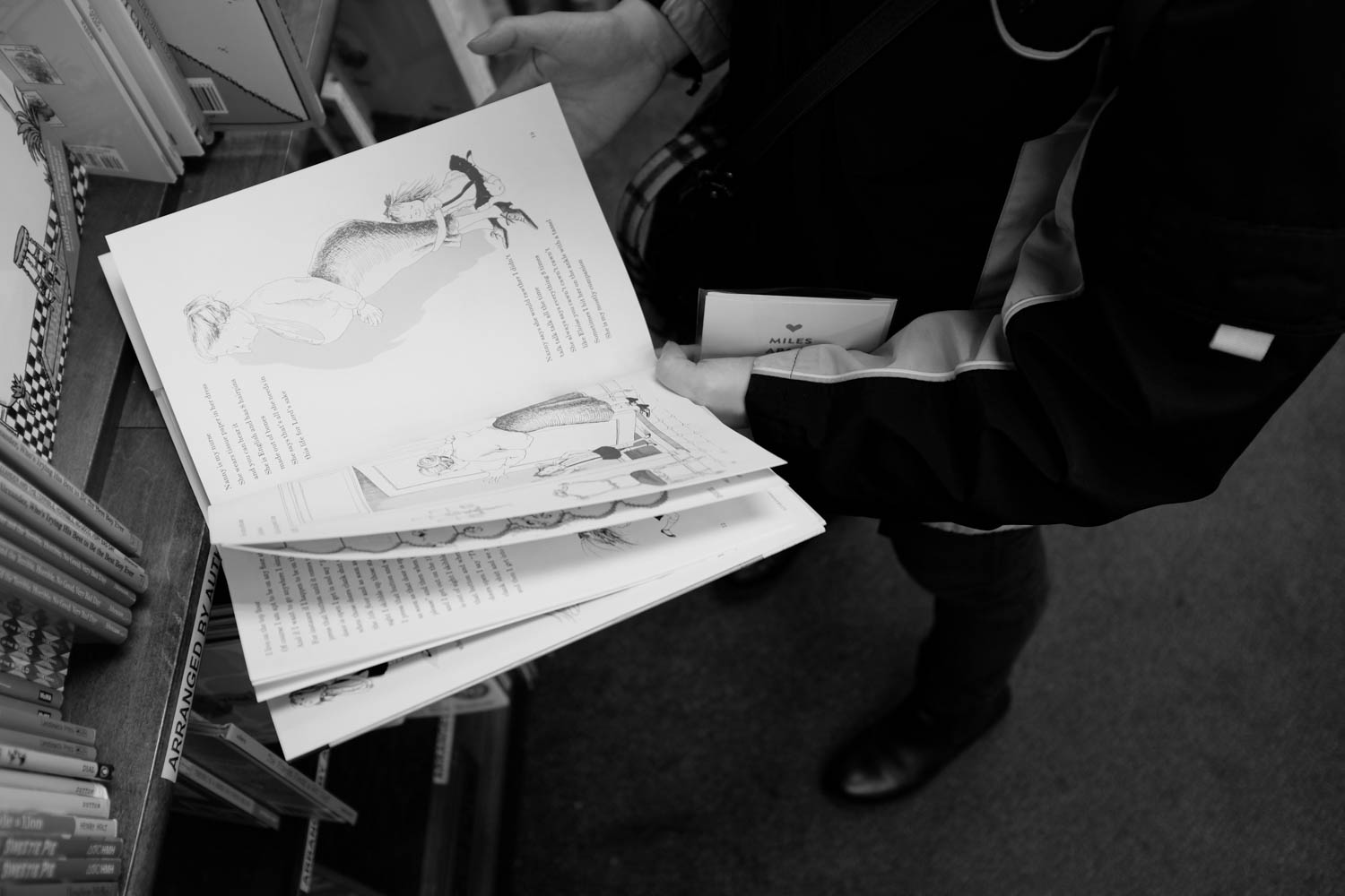 A top-down photograph of a girl flipping through the pages of the Children's book, "Eloise," at a local Manhattan book store.